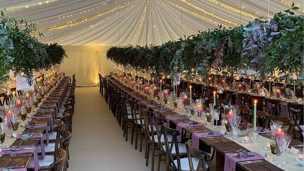 Wedding marquee set up with long tables with mauve table clothes and nature inspired marquee decoration