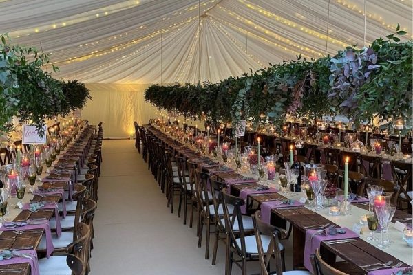 Wedding marquee set up with long tables with mauve table clothes and nature inspired marquee decoration